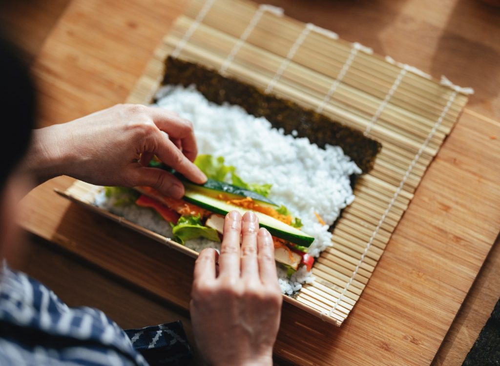 Woman rolling sushi on a mat