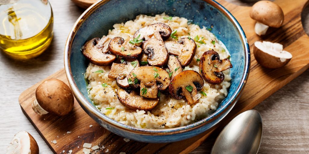 Risotto with brown champignon mushrooms on wooden background