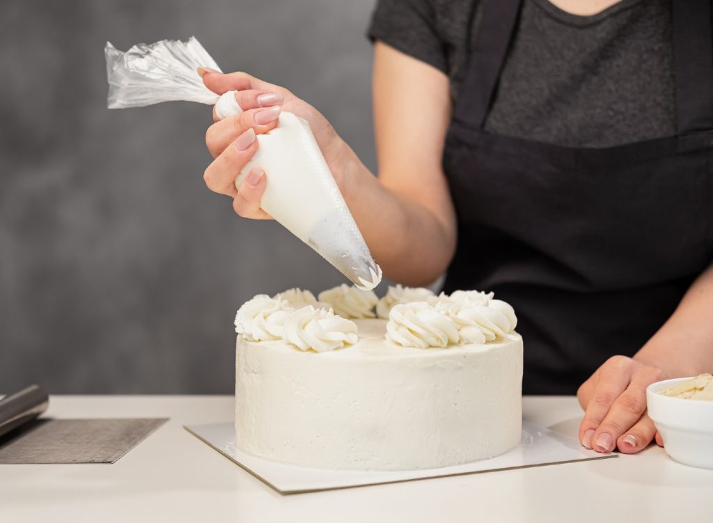 Woman putting frosting on a cake