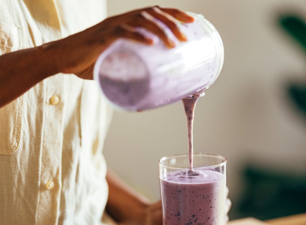 Woman pouring berry smoothie into a glass