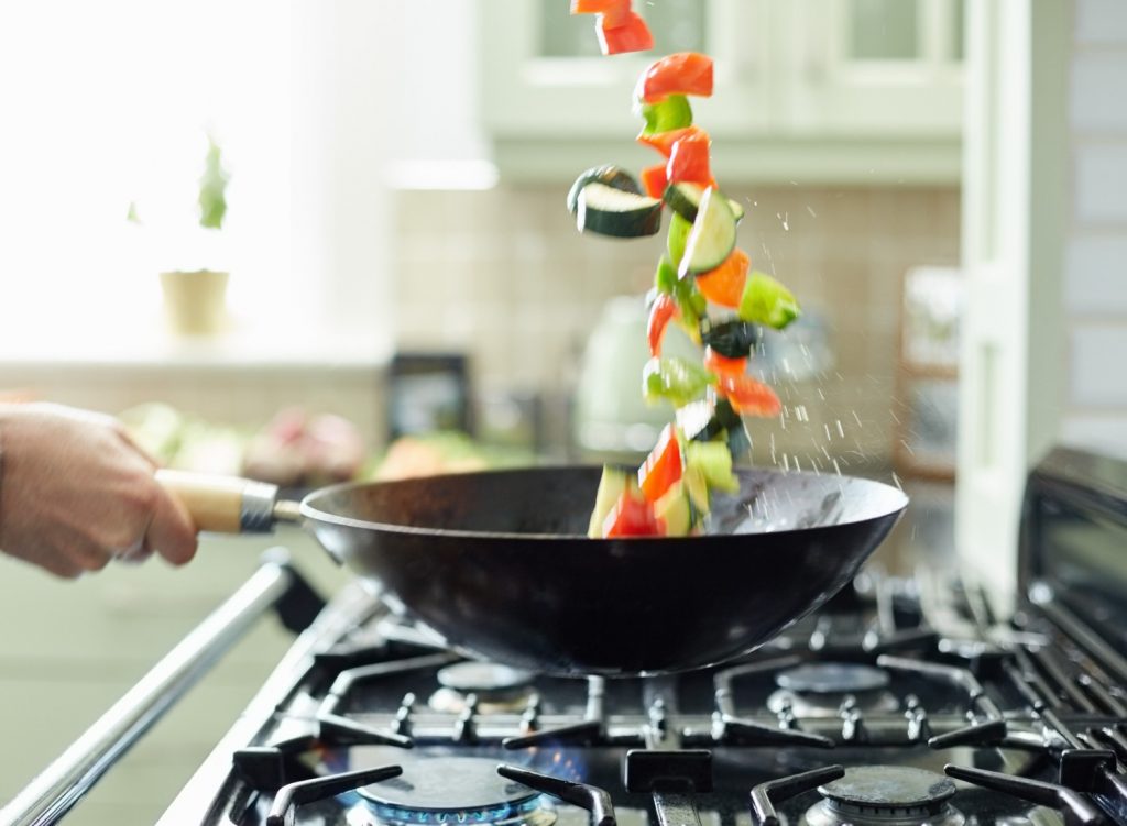 Man tossing vegetables in a cooking pan