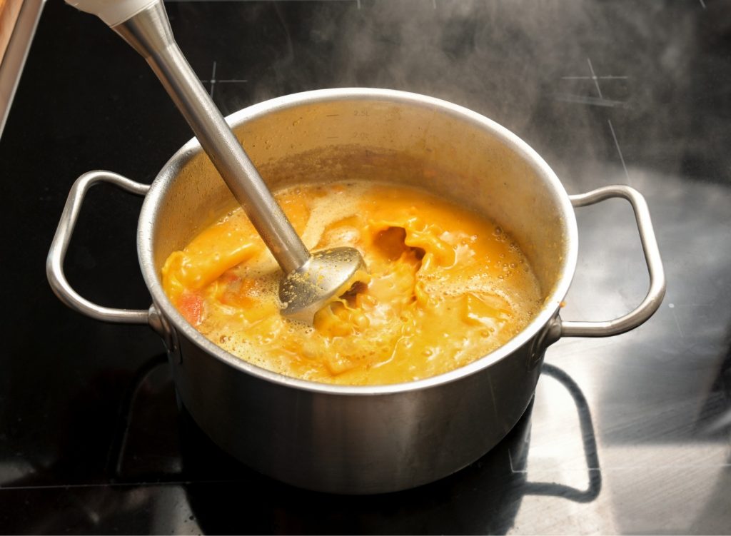 Immersion blender in pot of soup