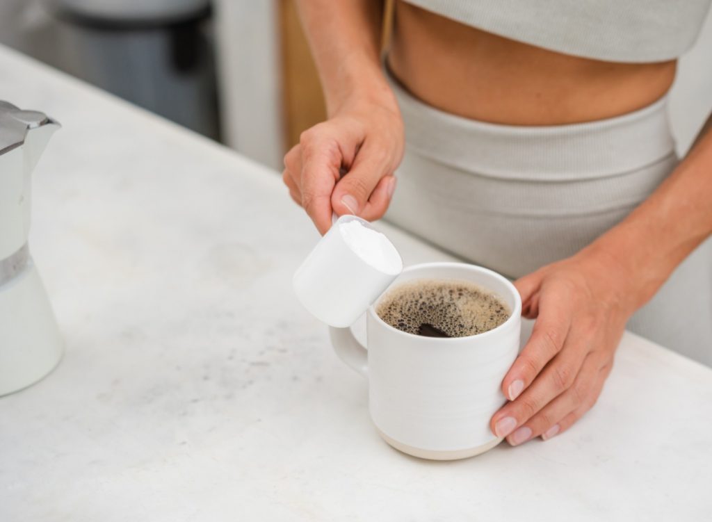 Woman adding protein powder to coffee