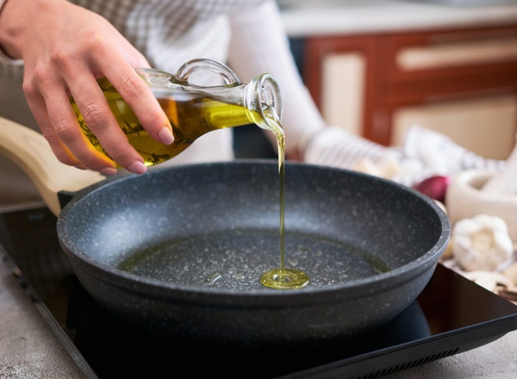 Woman pouring olive oil into a pan