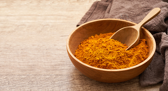 Curry powder close up a pile of ground turmeric powder or curcumin powder in wood plate and scoop on wooden table background. turmeric or curcumin powder
