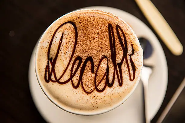 A cup of medium roast decaf coffee with the word "decaf" written in syrup.