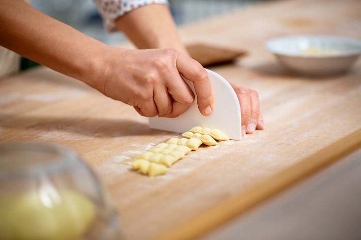 A person cutting dough using a dough cutter.