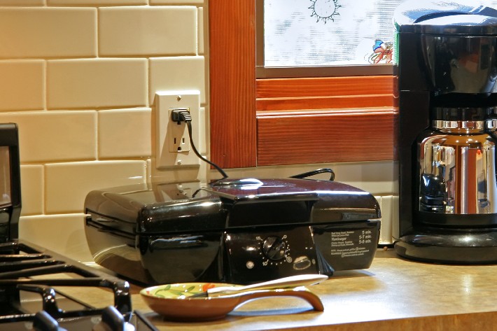 An image of a spoon holder on a kitchen counter alongside a couple of appliances.